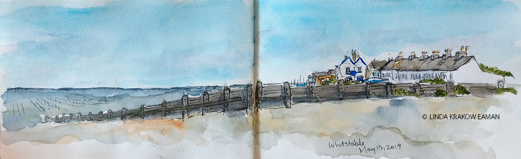 Watercolor and ink sketch of gravel beach, wood groyne going down to ocean, and a row of white houses. 